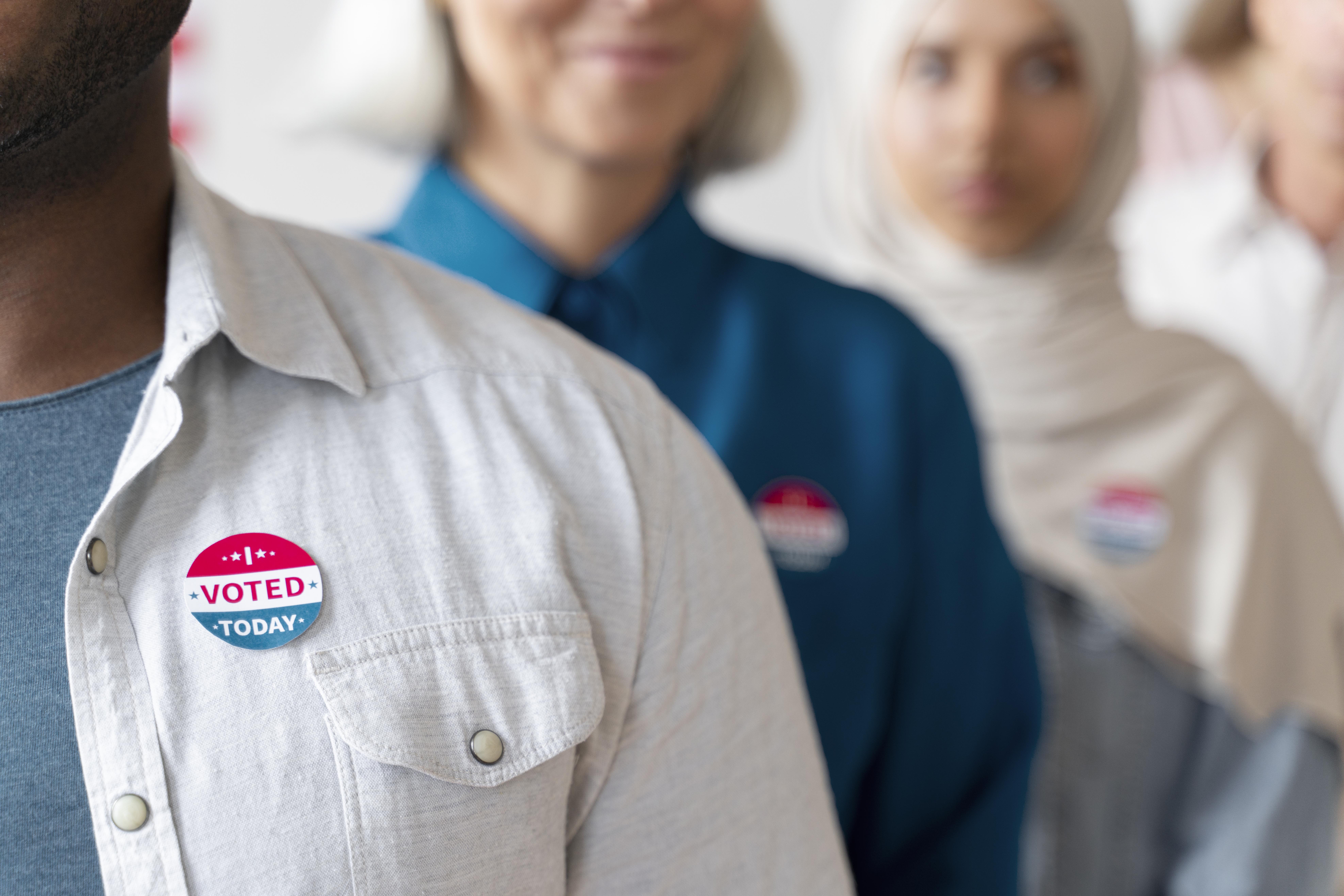 personas con pin de "He votado hoy"